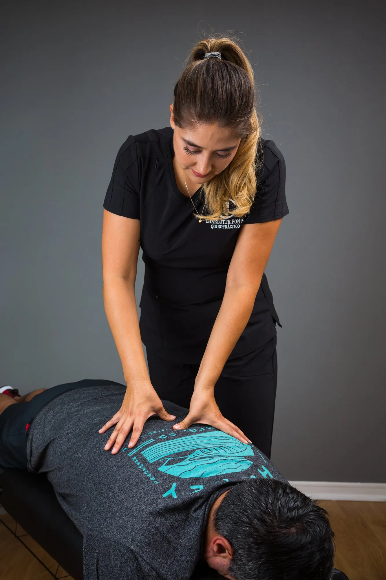 Charlotte, de pie, trabajando con las dos manos sobre la espalda de un paciente tendido en la camilla